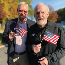 two senior men holding American flags